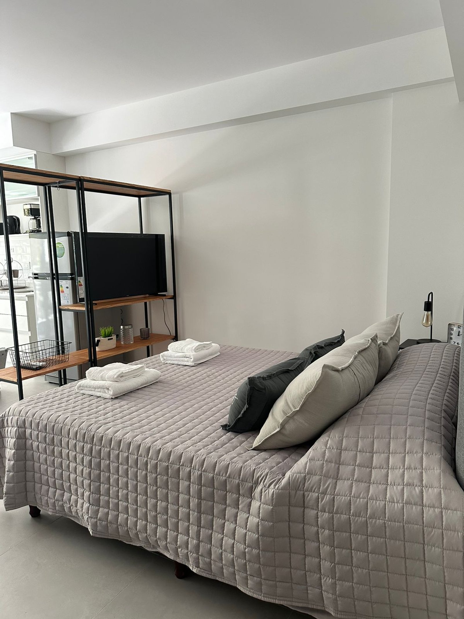 Dormitorio moderno con cama acolchada gris, estantería de metal y madera — proyecto Airbnb, por Estudio Hirsch, en Buenos Aires